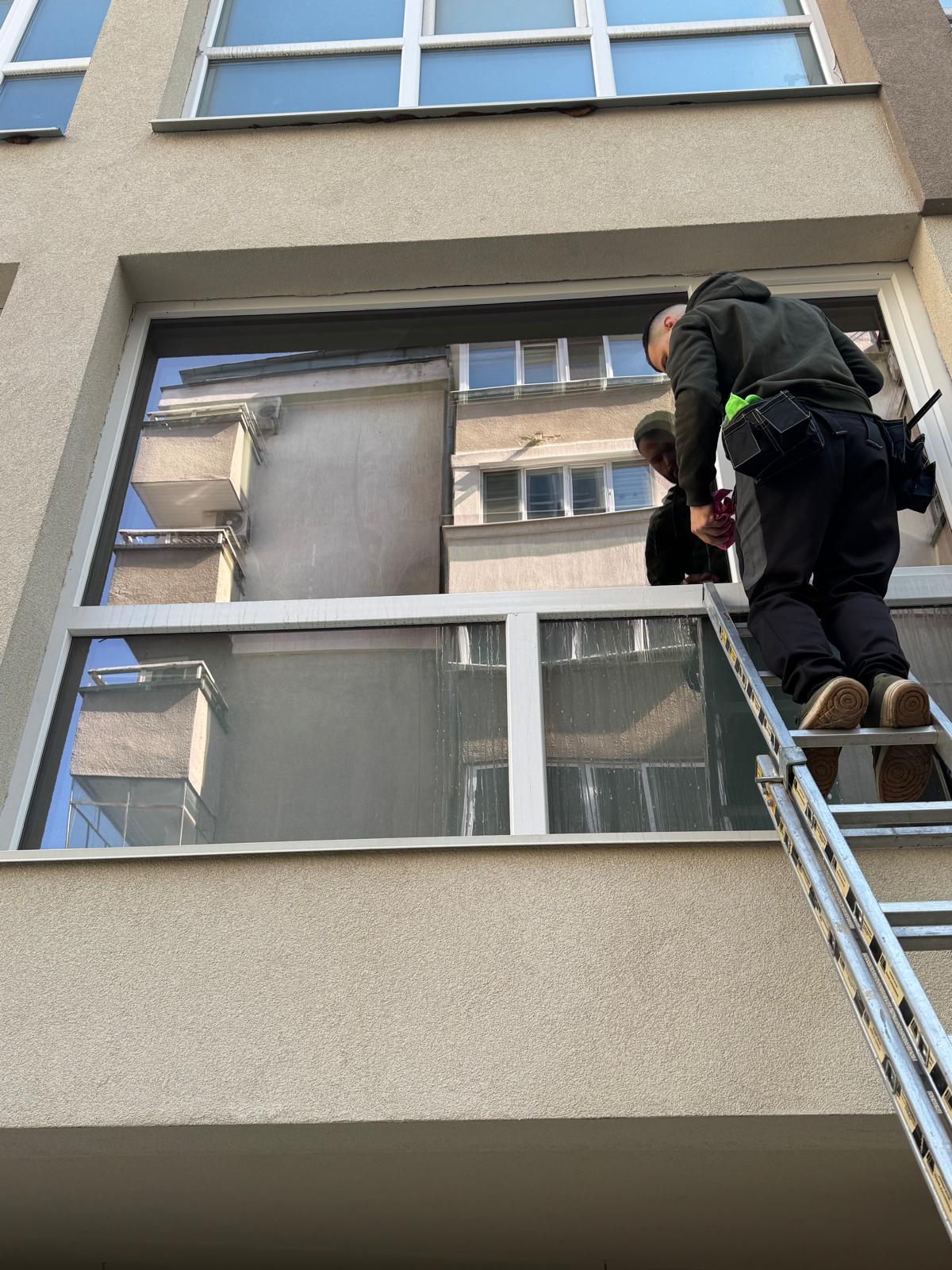 Почистване на прозорци на жилищна сграда с стълба